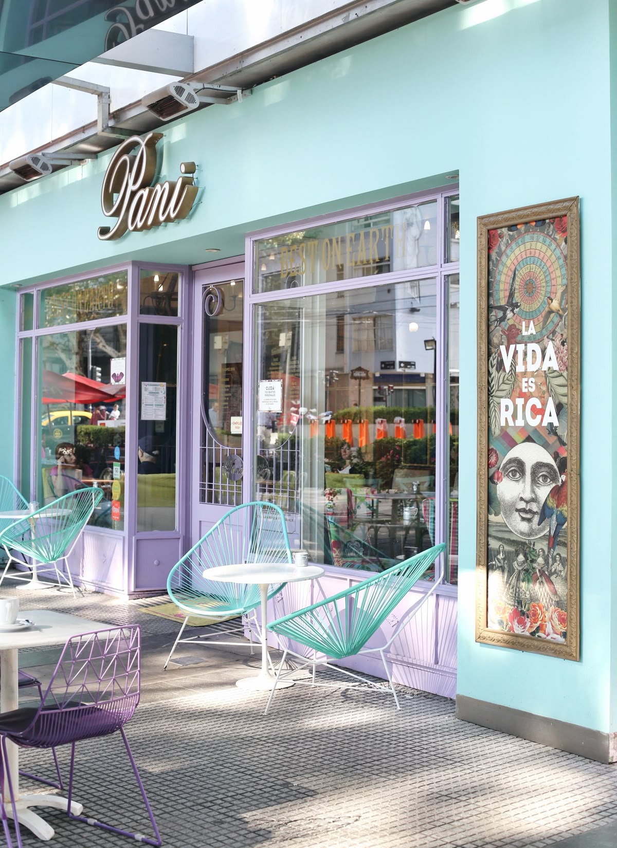 Pastel storefront of a café with turquoise wire chairs in Palermo