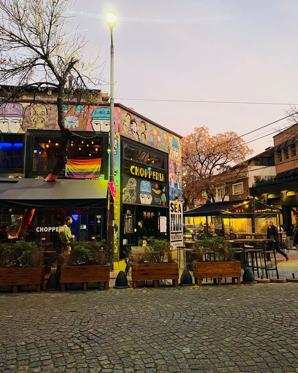 Street-art covered corner bar on a cobblestone square in Palermo at dusk